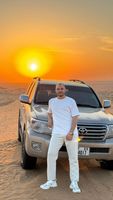 Mann vor Geländewagen bei Sonnenuntergang in der Wüste